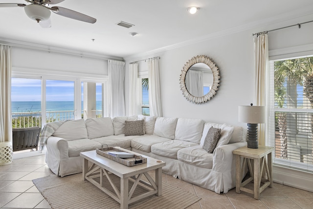 tiled living room featuring a healthy amount of sunlight, a water view, and crown molding