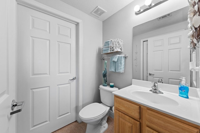 bathroom with toilet, vanity, a textured ceiling, and tile patterned flooring