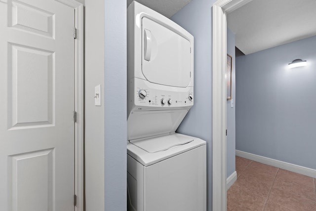 washroom featuring stacked washing maching and dryer, a textured ceiling, and light tile patterned flooring