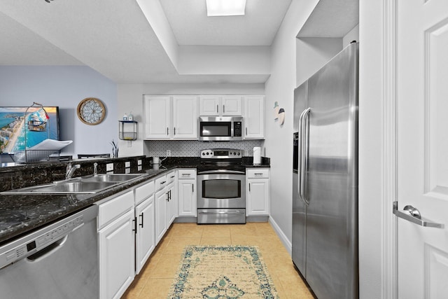 112 Seascape Dr Unit 2206, Miramar Beach, FL 32550 - kitchen featuring appliances with stainless steel finishes, a sink, light tile patterned floors, white cabinets, and tasteful backsplash