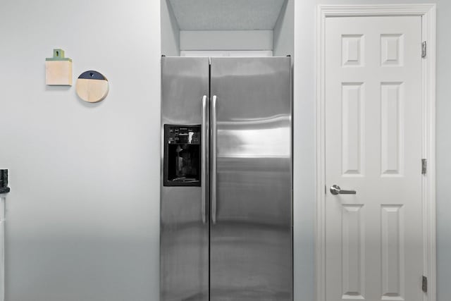 details featuring stainless steel refrigerator with ice dispenser and a textured ceiling