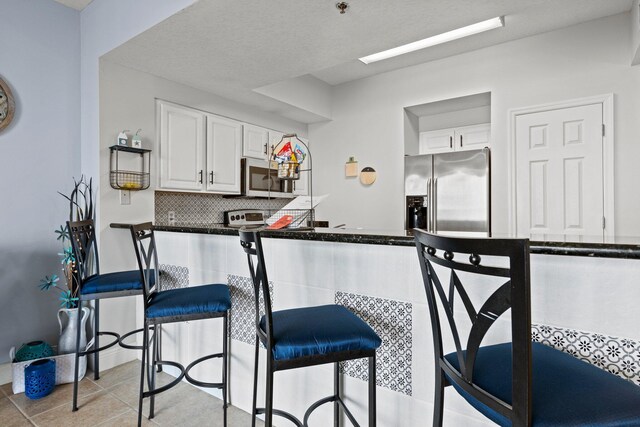 112 Seascape Dr Unit 2206, Miramar Beach, FL 32550 - kitchen with appliances with stainless steel finishes, white cabinets, dark countertops, and backsplash