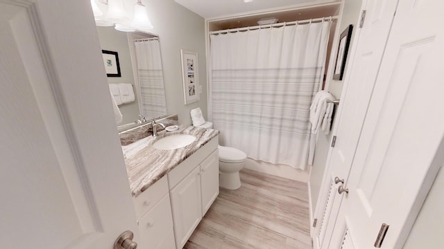 full bathroom featuring toilet, vanity, hardwood / wood-style flooring, and shower / bath combo with shower curtain