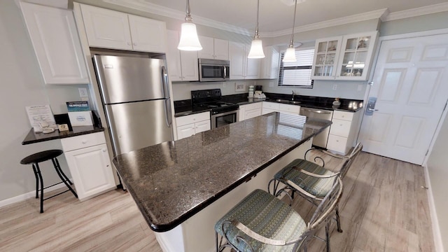 kitchen featuring white cabinets, a kitchen breakfast bar, appliances with stainless steel finishes, and a kitchen island