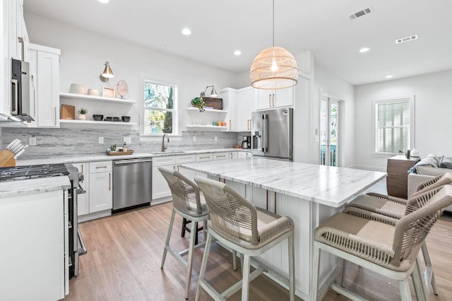 kitchen with tasteful backsplash, white cabinetry, appliances with stainless steel finishes, and a center island