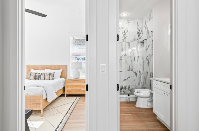 bedroom featuring light hardwood / wood-style flooring, ceiling fan, and connected bathroom