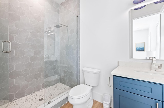 bathroom featuring vanity, hardwood / wood-style flooring, toilet, and a shower with door