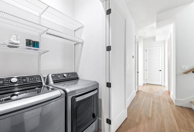 laundry room with light hardwood / wood-style floors and washing machine and dryer