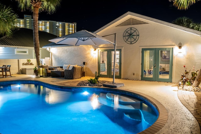 pool at twilight featuring a patio and french doors