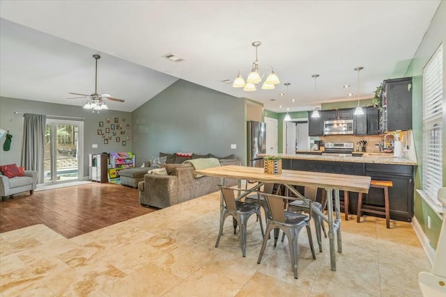 dining room with lofted ceiling, sink, ceiling fan with notable chandelier, and light wood-type flooring