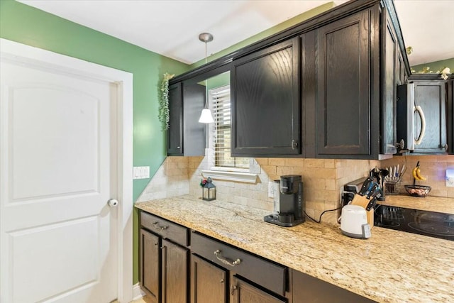 kitchen featuring decorative backsplash, dark brown cabinetry, decorative light fixtures, and light stone countertops