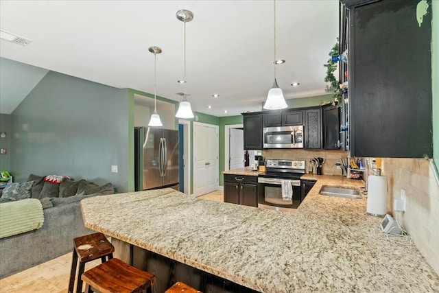 kitchen with kitchen peninsula, decorative backsplash, stainless steel appliances, and decorative light fixtures