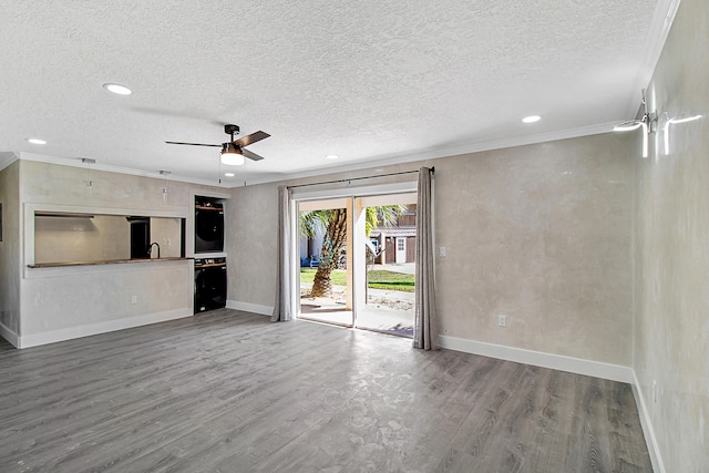 unfurnished living room with ceiling fan, crown molding, wood-type flooring, and a textured ceiling