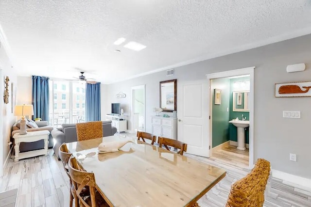 dining room featuring a textured ceiling, light hardwood / wood-style floors, ceiling fan, and sink