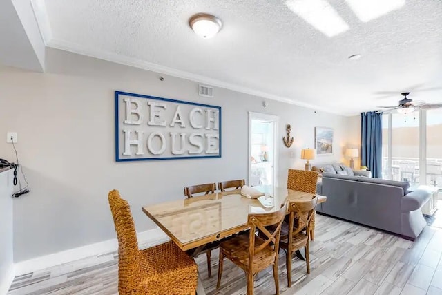 dining area with a textured ceiling, ceiling fan, light wood-style floors, crown molding, and baseboards