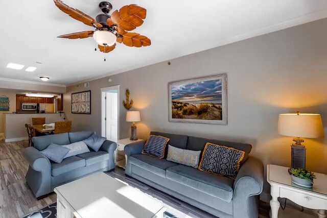 living room featuring hardwood / wood-style floors, ceiling fan, and crown molding