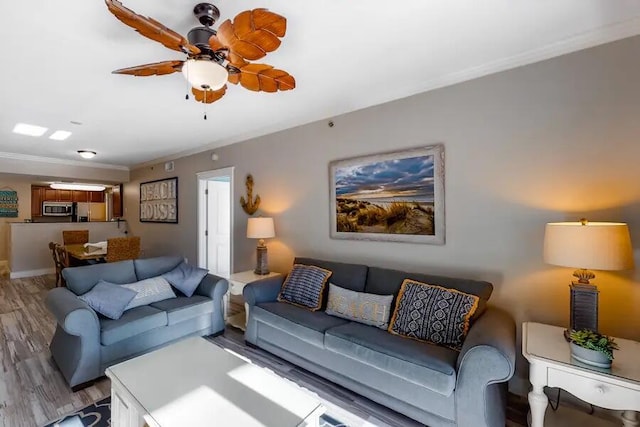 living room with light wood-type flooring, ornamental molding, and ceiling fan
