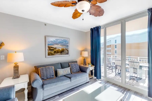living area with wood finished floors, a ceiling fan, and expansive windows
