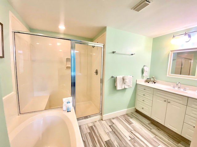 bathroom with hardwood / wood-style floors, vanity, and plus walk in shower