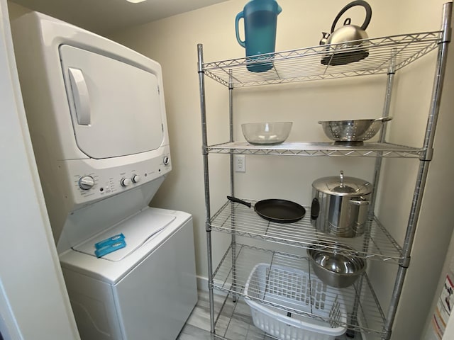 washroom featuring stacked washer and clothes dryer, baseboards, and light tile patterned flooring