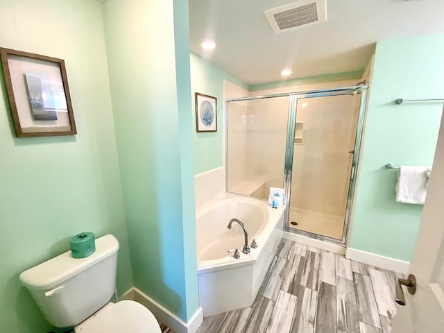 bathroom featuring toilet, plus walk in shower, and wood-type flooring