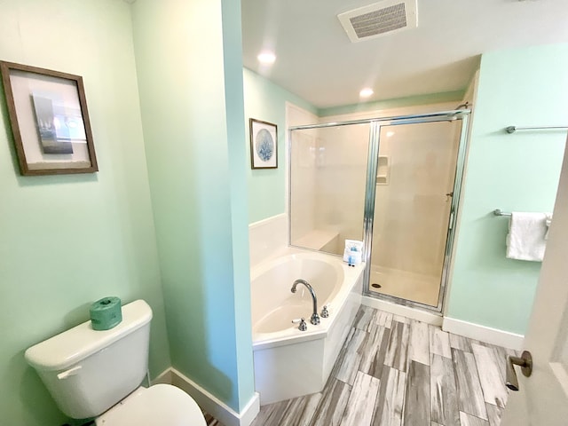 full bath with a bath, toilet, a shower stall, wood finished floors, and baseboards