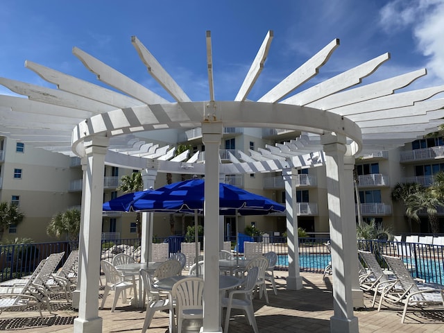 view of patio with a pergola, fence, and a community pool