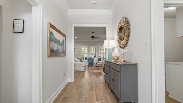 corridor with light hardwood / wood-style floors and crown molding