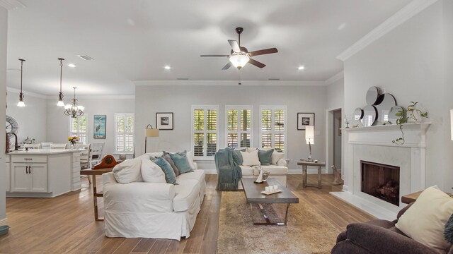 living room featuring ceiling fan with notable chandelier, light hardwood / wood-style floors, and ornamental molding