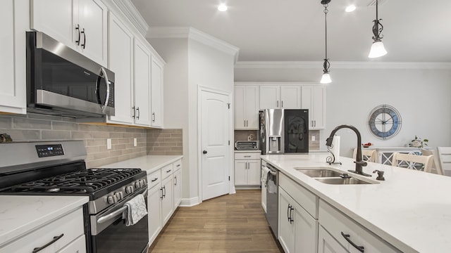 kitchen with pendant lighting, white cabinets, sink, hardwood / wood-style flooring, and stainless steel appliances