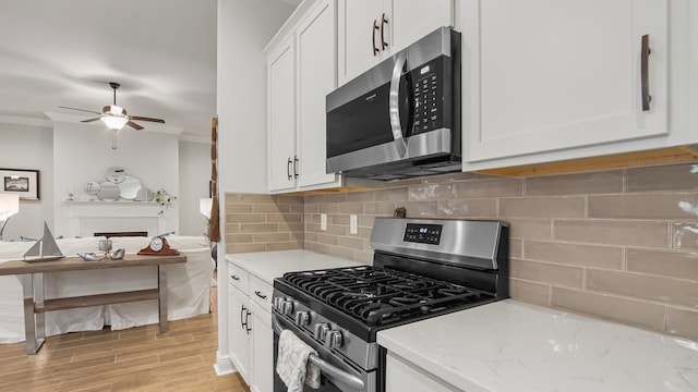 kitchen with light hardwood / wood-style flooring, decorative backsplash, light stone countertops, white cabinetry, and stainless steel appliances