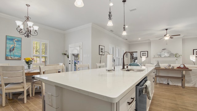 kitchen with pendant lighting, light hardwood / wood-style floors, sink, and an island with sink