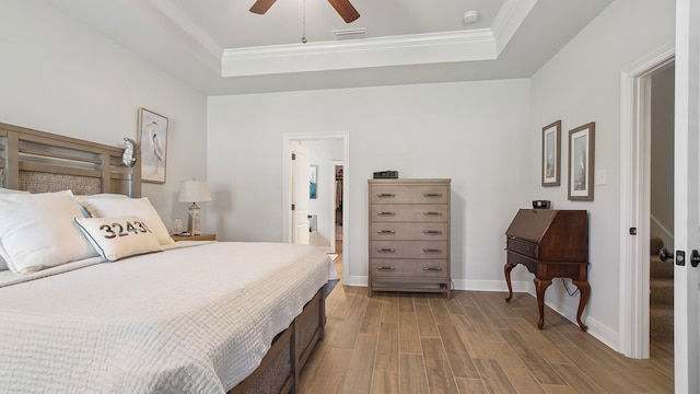 bedroom featuring a tray ceiling, ceiling fan, hardwood / wood-style floors, and ornamental molding