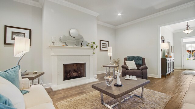 living room with crown molding, a high end fireplace, and light wood-type flooring