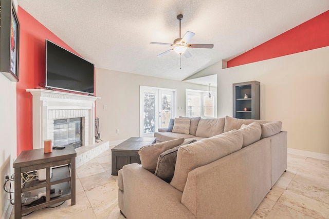 living room with a textured ceiling, ceiling fan, lofted ceiling, and a fireplace