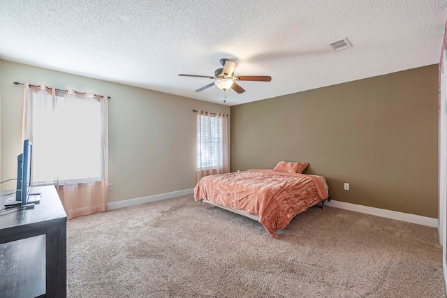 carpeted bedroom featuring a textured ceiling and ceiling fan