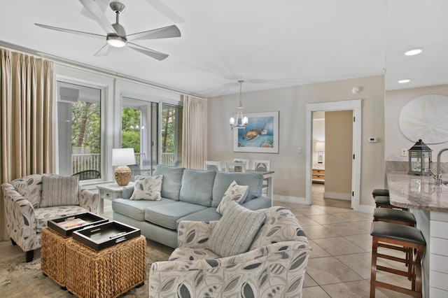 tiled living room with ceiling fan with notable chandelier