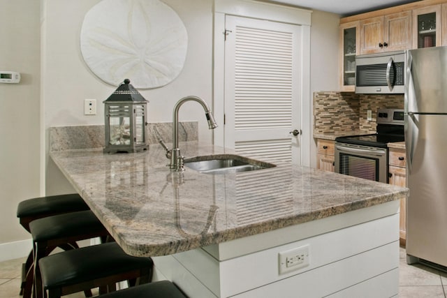 kitchen featuring stainless steel appliances, sink, a breakfast bar, and light stone counters