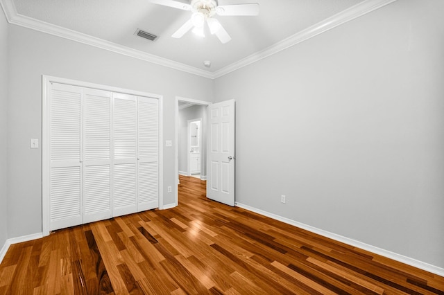 unfurnished bedroom featuring ceiling fan, a closet, ornamental molding, and hardwood / wood-style flooring