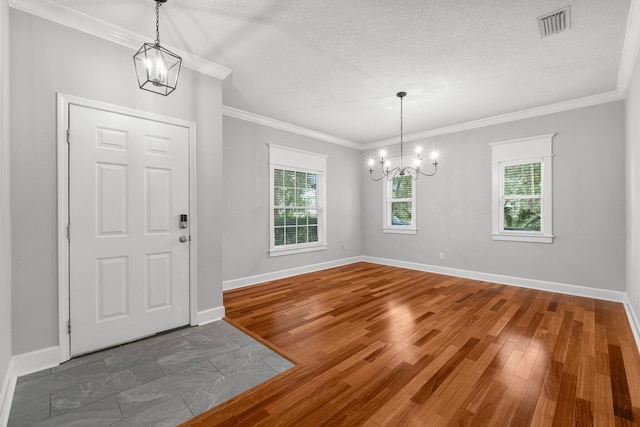 foyer entrance featuring ornamental molding, wood-type flooring, a textured ceiling, and an inviting chandelier