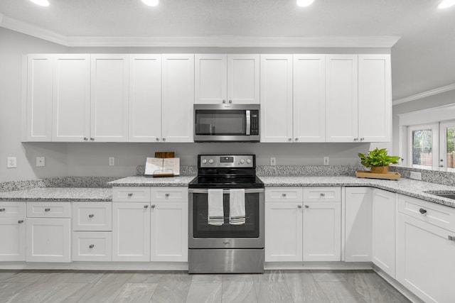 kitchen with light stone countertops, white cabinetry, stainless steel appliances, and ornamental molding