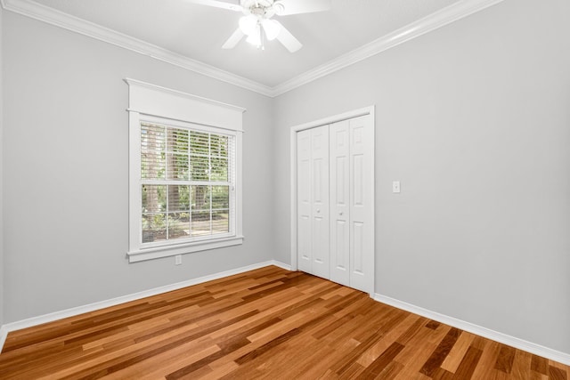 unfurnished bedroom with a closet, ceiling fan, crown molding, and wood-type flooring