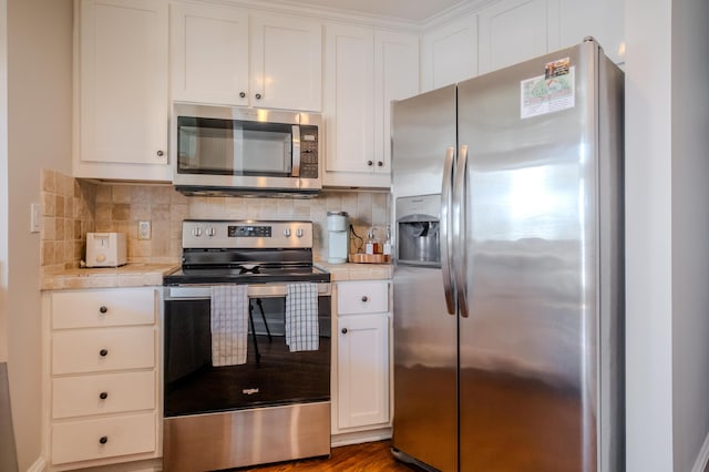 kitchen featuring white cabinets, backsplash, wood-type flooring, and stainless steel appliances