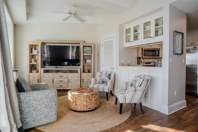 living room featuring dark hardwood / wood-style flooring, ceiling fan, and sink