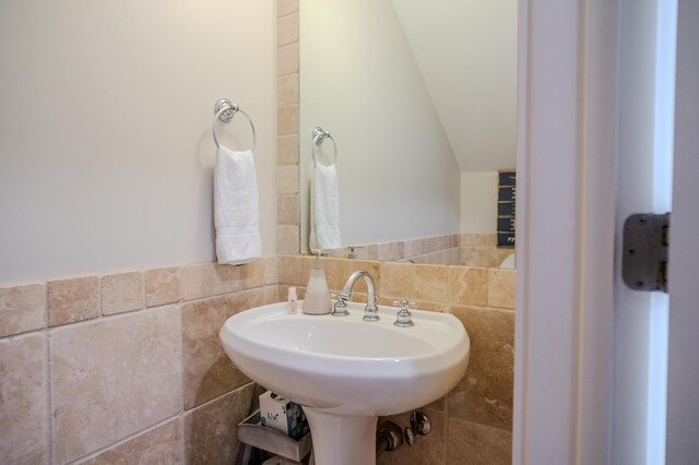 bathroom featuring sink, tile walls, and vaulted ceiling