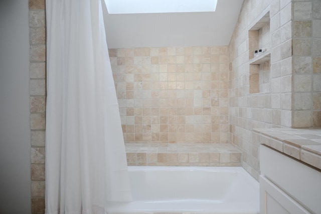 bathroom featuring vanity, a skylight, and shower / bathtub combination with curtain