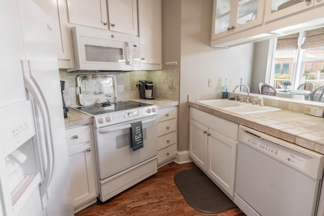 kitchen featuring white appliances, sink, tasteful backsplash, dark hardwood / wood-style flooring, and white cabinetry