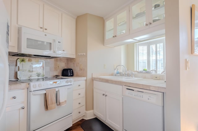 kitchen with decorative backsplash, white cabinetry, sink, and white appliances