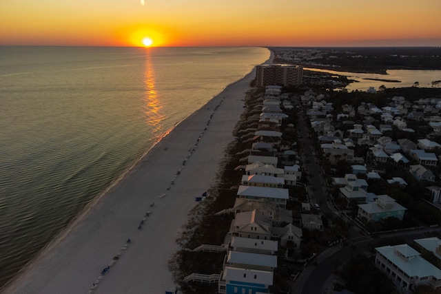 aerial view at dusk with a water view and a view of the beach