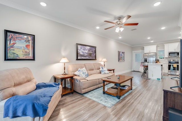 living room with light hardwood / wood-style flooring, ceiling fan, and crown molding